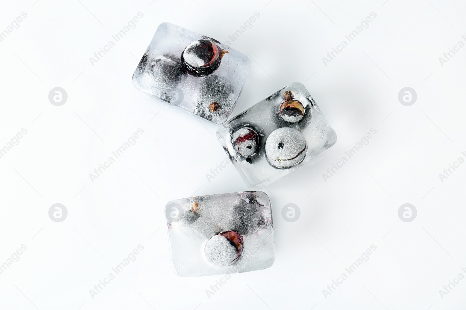 Photo of Fresh berries frozen in ice cubes on white background