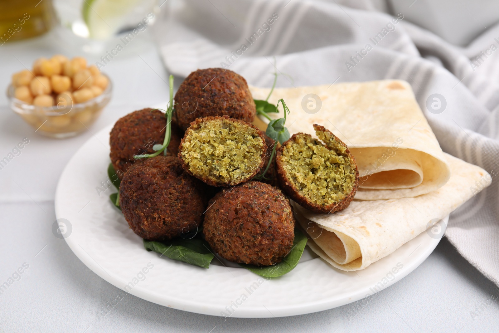 Photo of Delicious falafel balls, herbs and lavash on white table