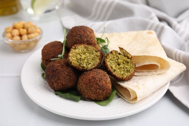 Delicious falafel balls, herbs and lavash on white table