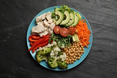 Photo of Balanced diet and healthy foods. Plate with different delicious products on black table, top view