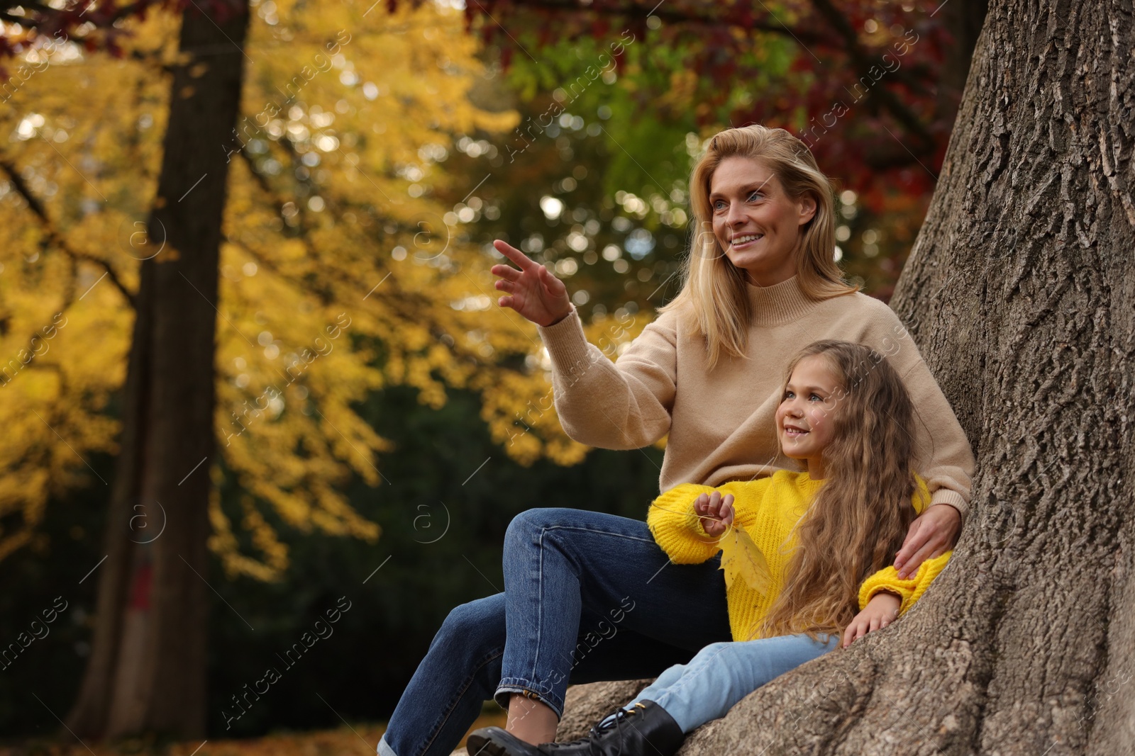 Photo of Happy mother spending time together with her daughter in autumn park. Space for text
