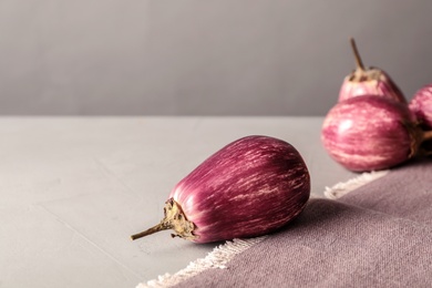 Photo of Ripe eggplants and towel on light grey table