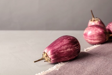 Ripe eggplants and towel on light grey table