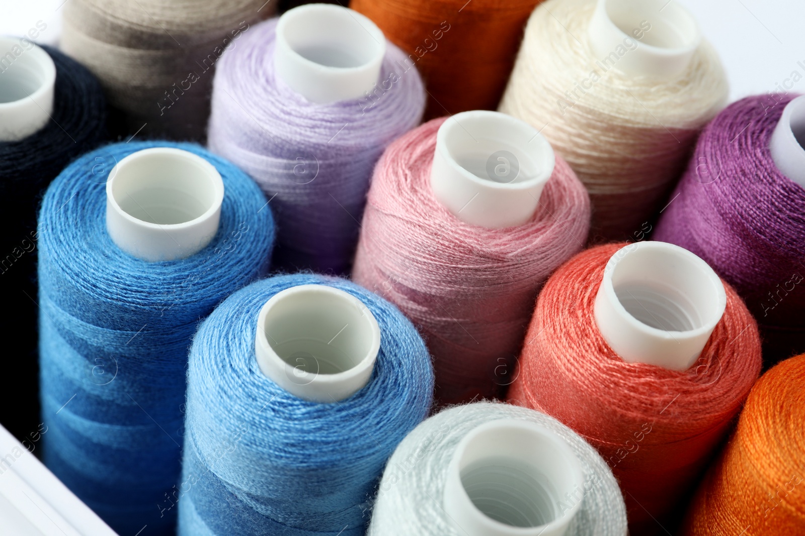 Photo of Set of different colorful sewing threads in box, closeup