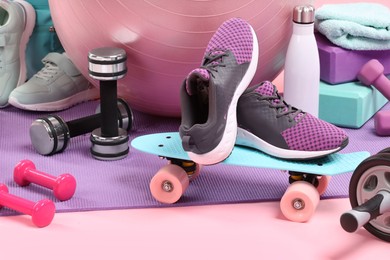 Many different sports equipment on pink background