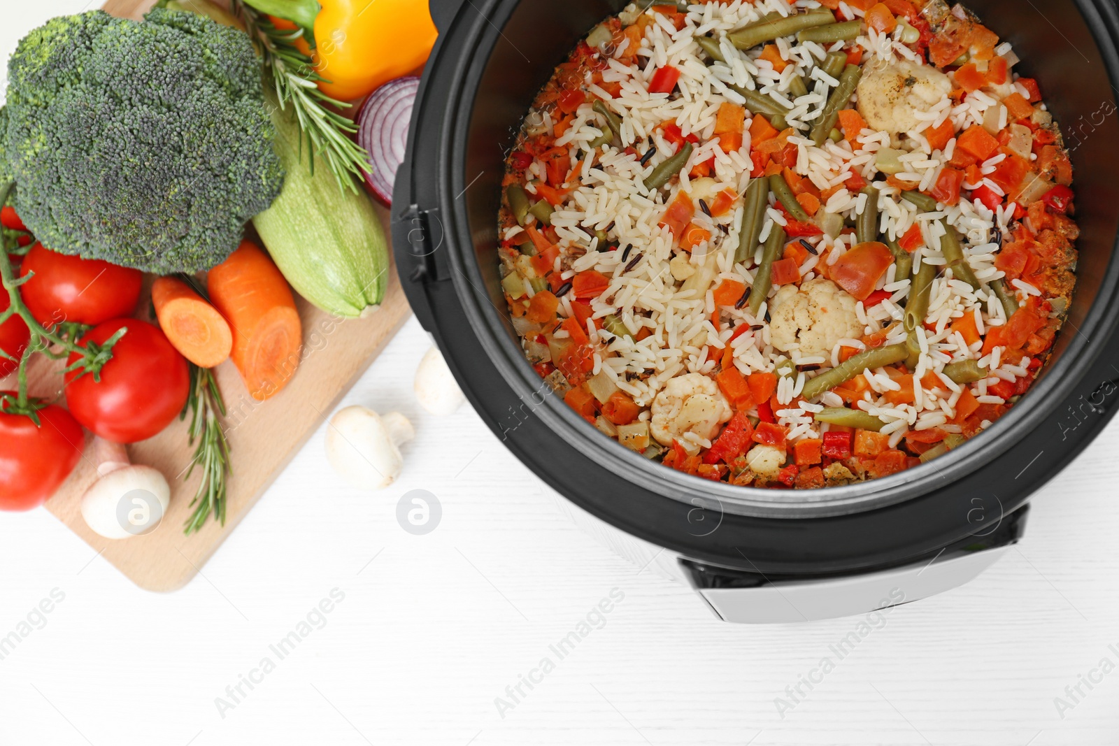 Photo of Prepared rice with vegetables in multi cooker on kitchen table, above view