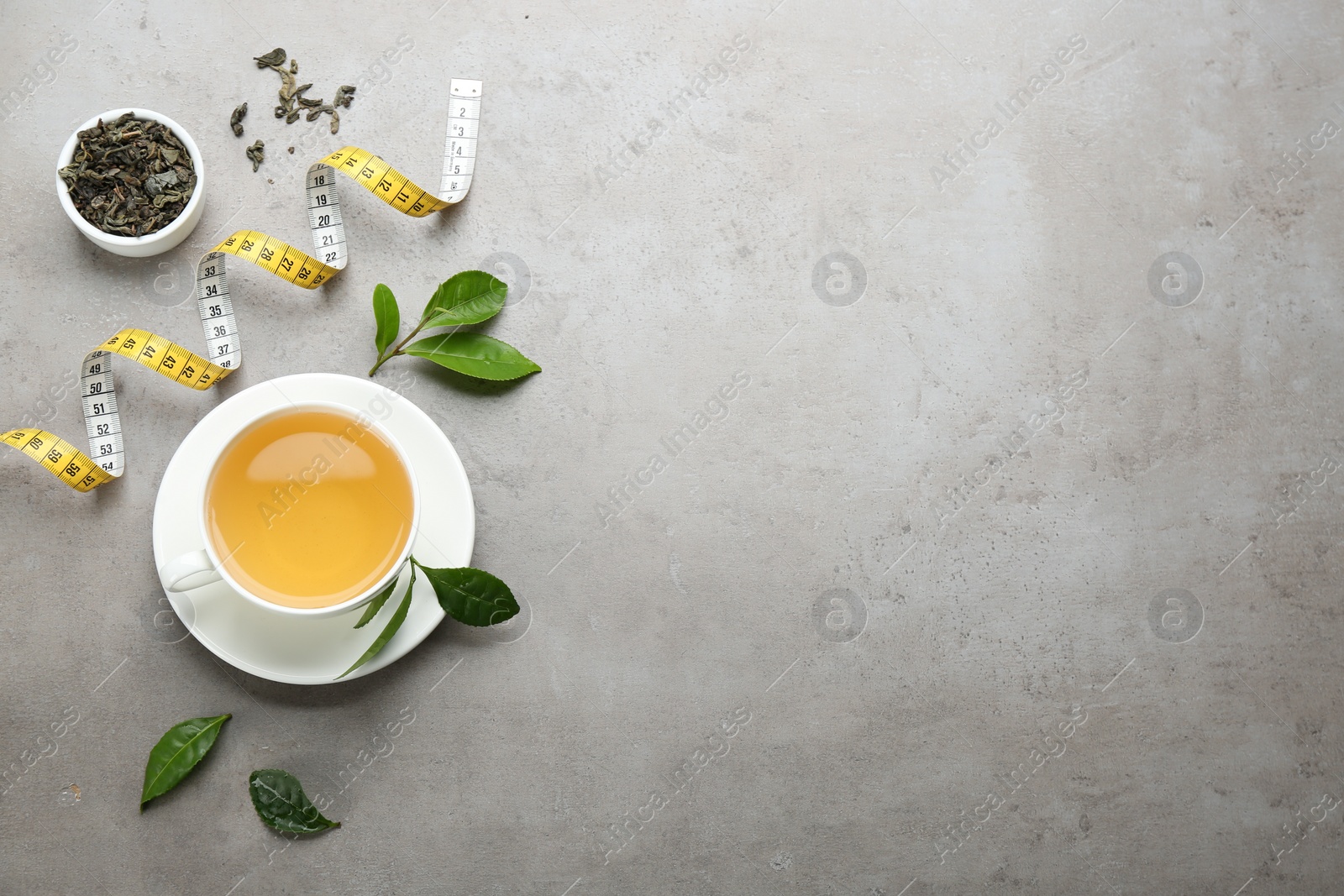 Photo of Flat lay composition with herbal diet tea and measuring tape on light table. Space for text