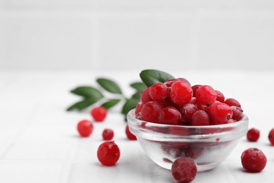 Photo of Frozen red cranberries in bowl on white table, closeup. Space for text