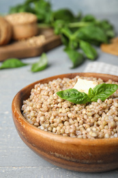 Tasty buckwheat porridge with butter on grey wooden table, closeup