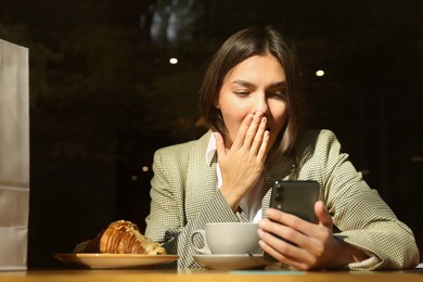 Photo of Special Promotion. Emotional young woman using smartphone at table in cafe