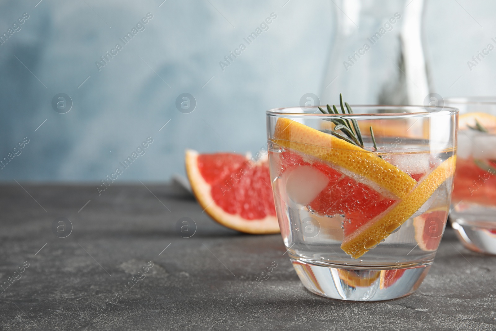 Photo of Glass of infused water with grapefruit slices on table. Space for text