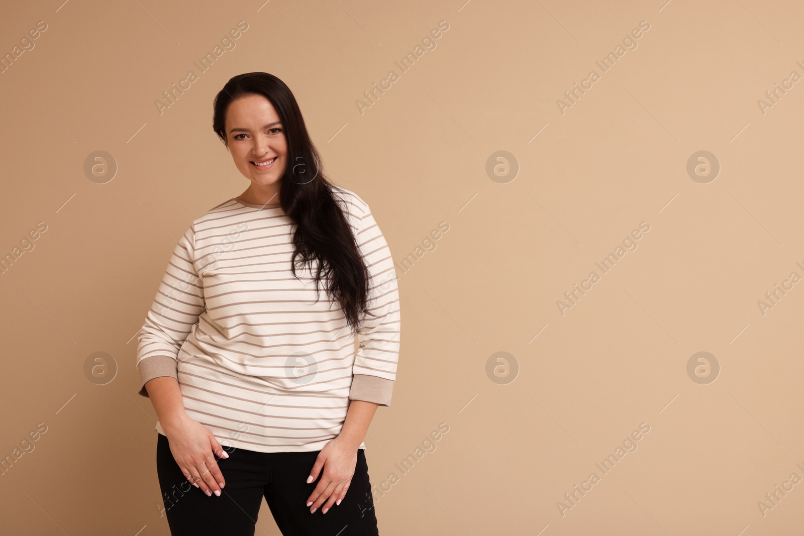 Photo of Beautiful overweight woman with charming smile on beige background. Space for text