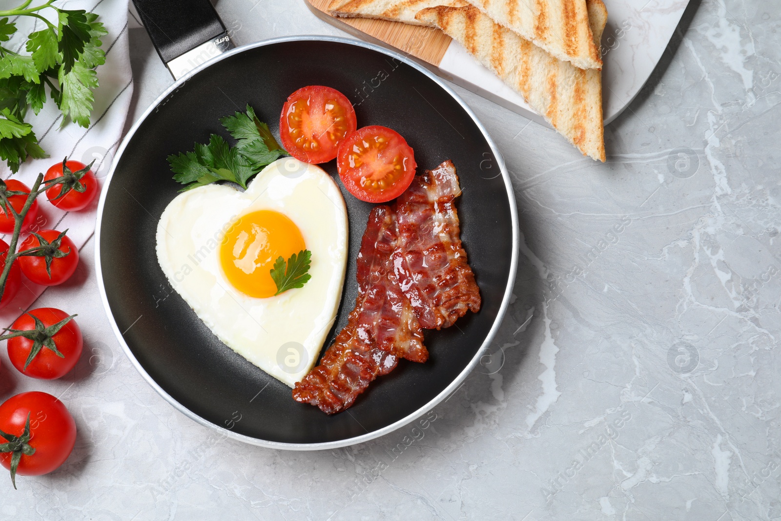 Photo of Tasty breakfast with heart shaped fried egg on grey table, flat lay