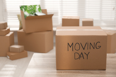 Photo of Cardboard box with words MOVING DAY on wooden table