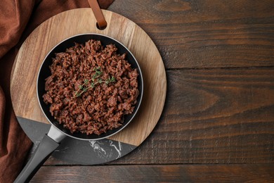 Photo of Fried ground meat and thyme in frying pan on wooden table, top view. Space for text