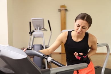 Young woman having heart attack on treadmill in gym