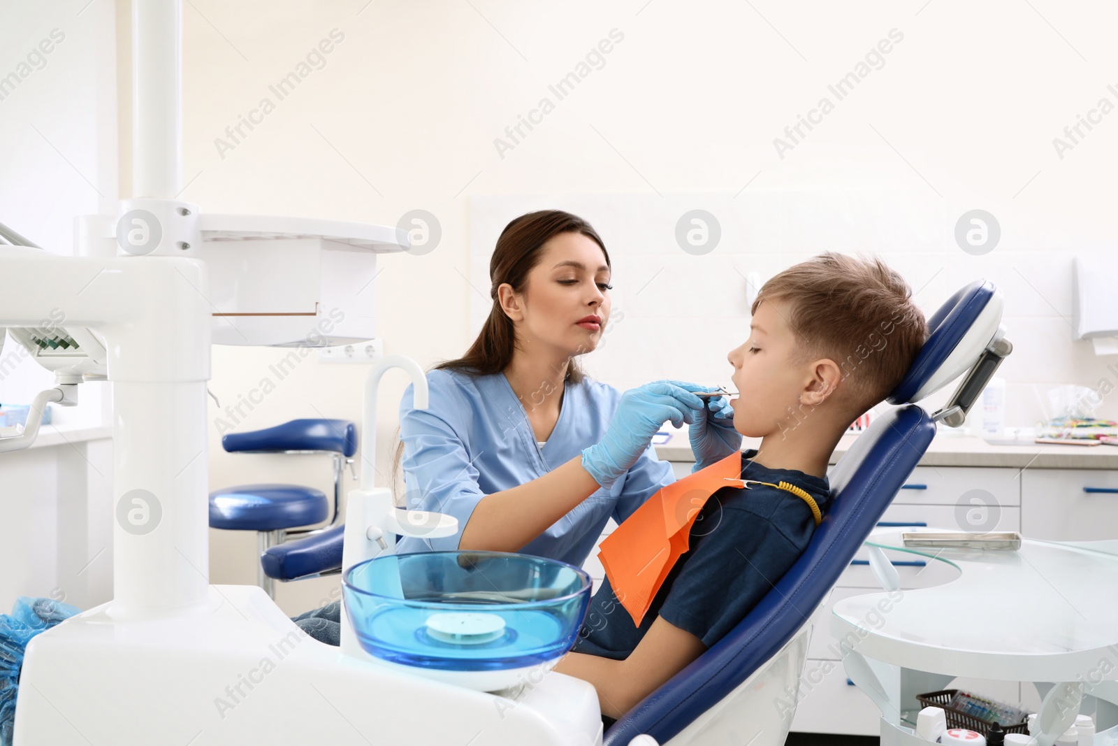 Photo of Professional dentist working with little boy in clinic