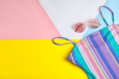 Flat lay composition with one-piece swimsuit and sunglasses on color background, space for text. Beach objects