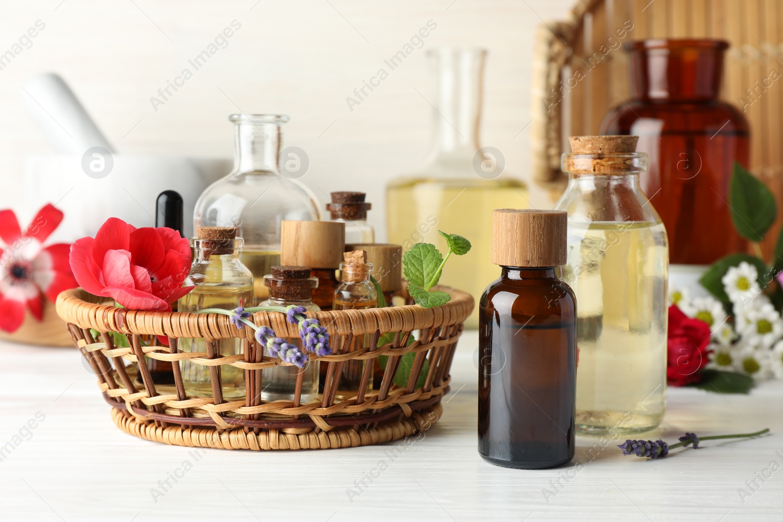 Photo of Aromatherapy. Different essential oils and flowers on white wooden table