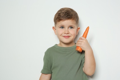 Photo of Adorable little boy with carrot on white background. Space for text