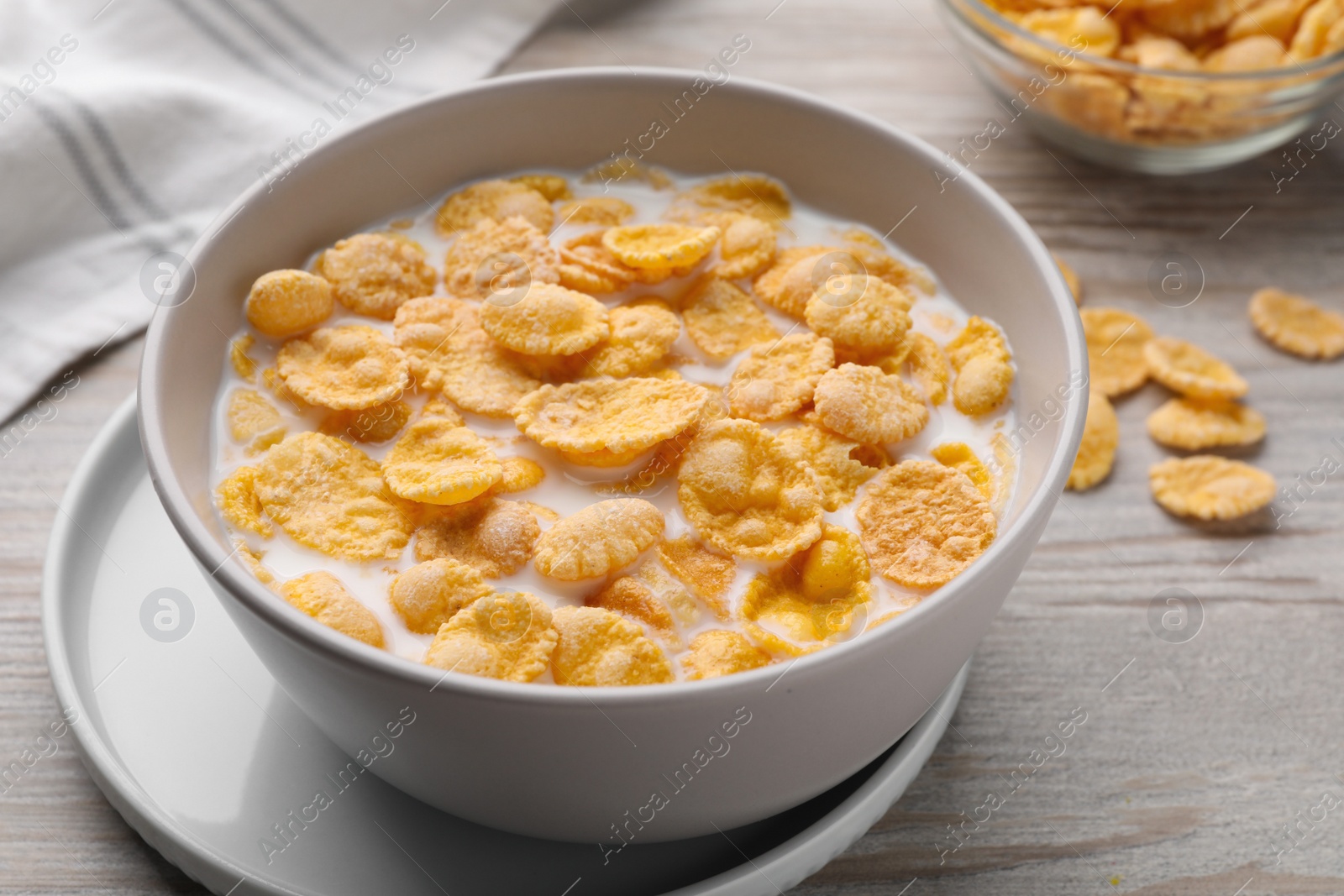 Photo of Tasty cornflakes with milk in bowl on wooden table, closeup