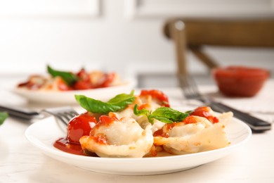 Tasty ravioli with tomato sauce served on white table