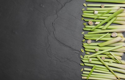Photo of Fresh lemongrass stalks on black table, flat lay. Space for text