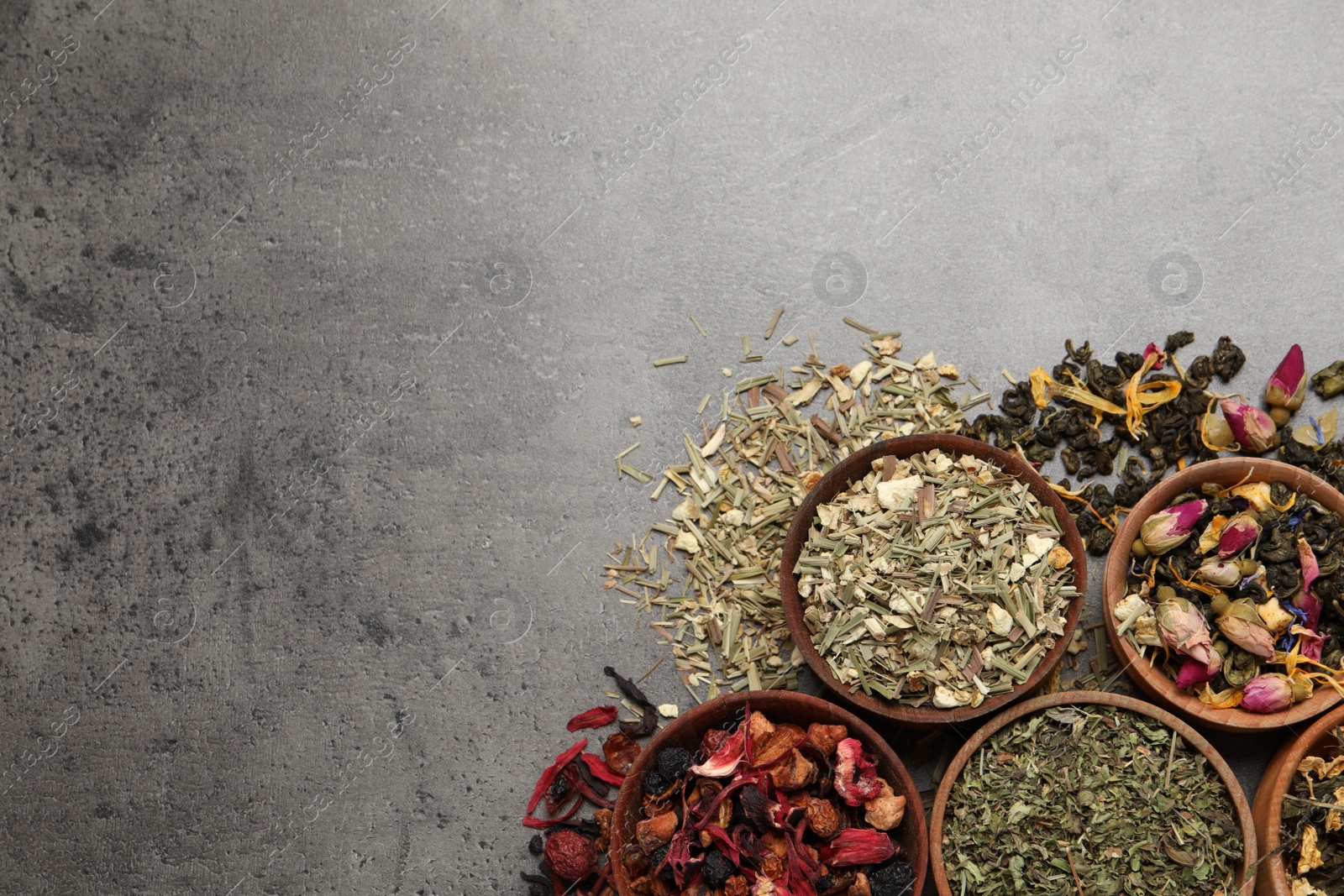 Photo of Flat lay composition with different dry teas on grey table, space for text