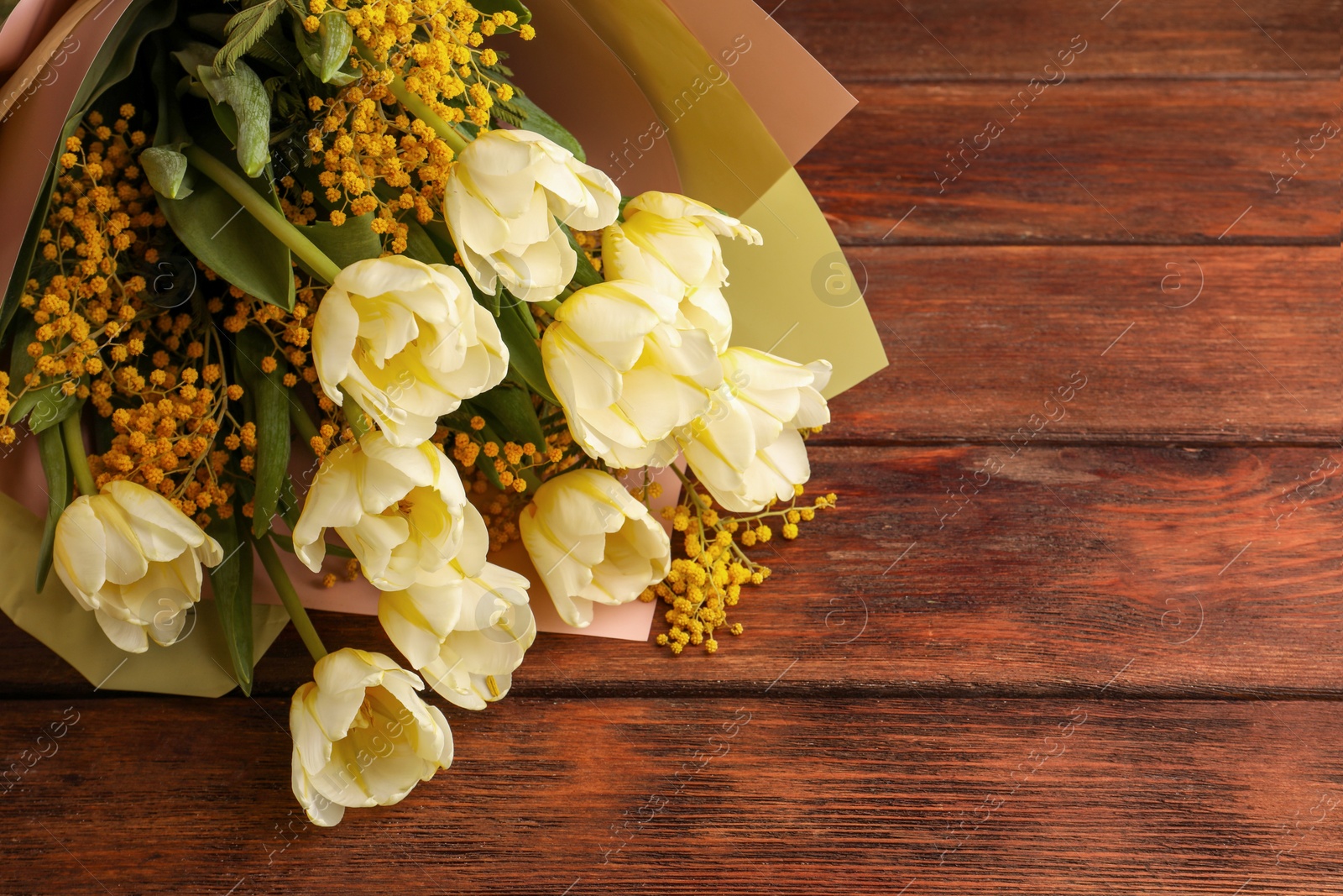 Photo of Bouquet with beautiful tulips and mimosa flowers on wooden table. Space for text