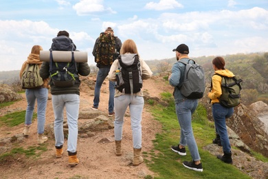 Group of hikers with backpacks climbing up mountains