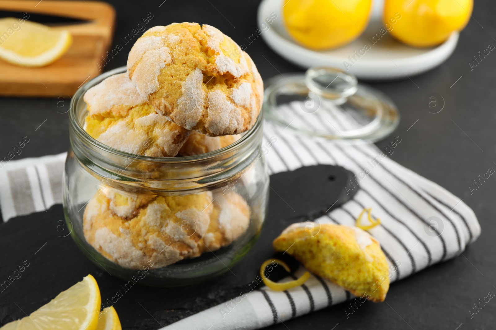 Photo of Delicious lemon cookies in glass jar on black table, space for text