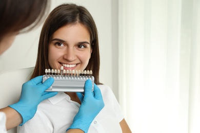 Doctor checking young woman's teeth color in clinic. Cosmetic dentistry