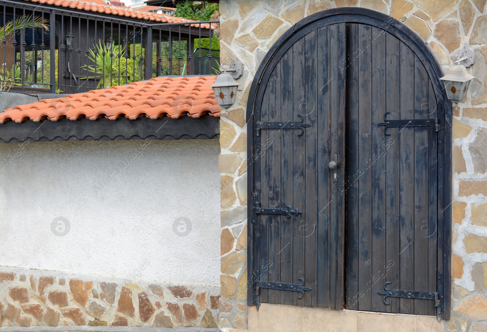 Photo of Entrance of building with beautiful arched wooden door in stone wall outdoors