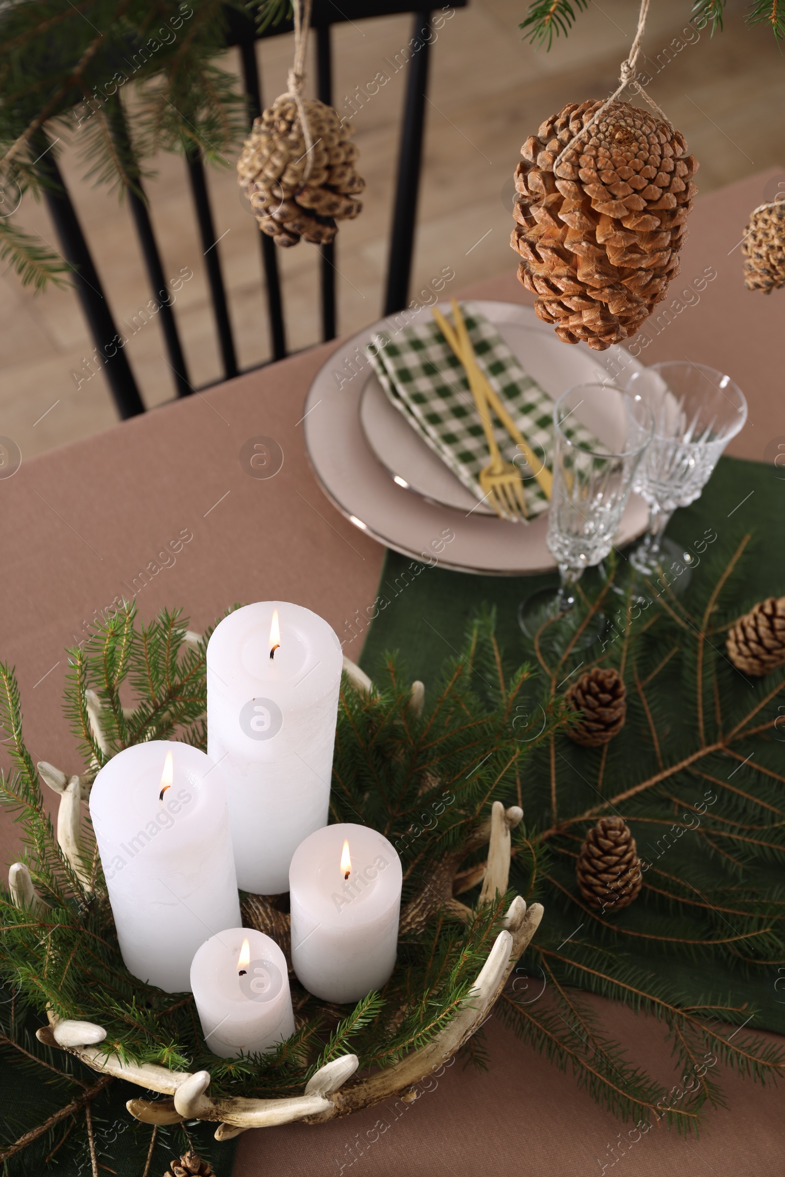 Photo of Christmas table setting with burning candles and other festive decor