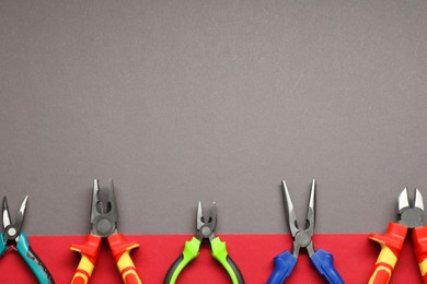 Photo of Different pliers on color background, flat lay. Space for text