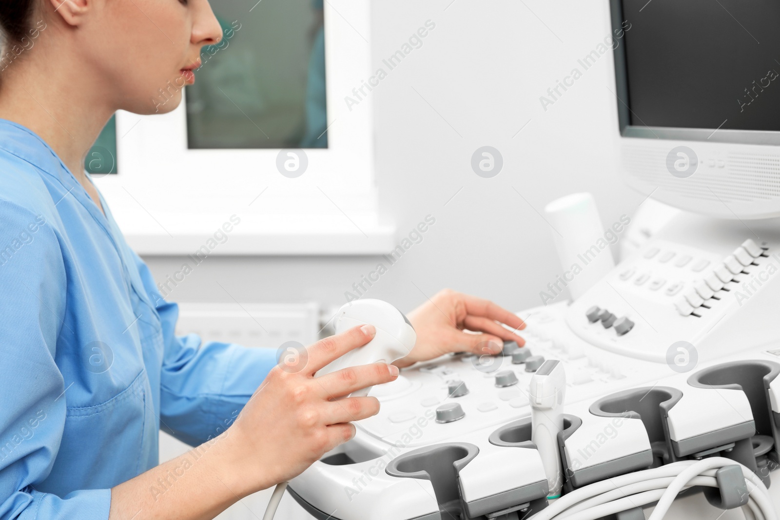 Photo of Sonographer operating modern ultrasound machine in clinic, closeup