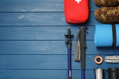 Photo of Flat lay composition with trekking poles and other hiking equipment on blue wooden background, space for text