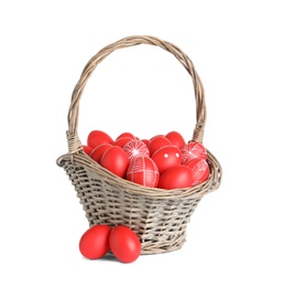 Photo of Wicker basket with painted red Easter eggs on white background