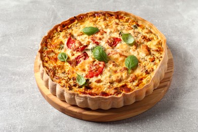 Photo of Tasty quiche with tomatoes, basil and cheese on light table