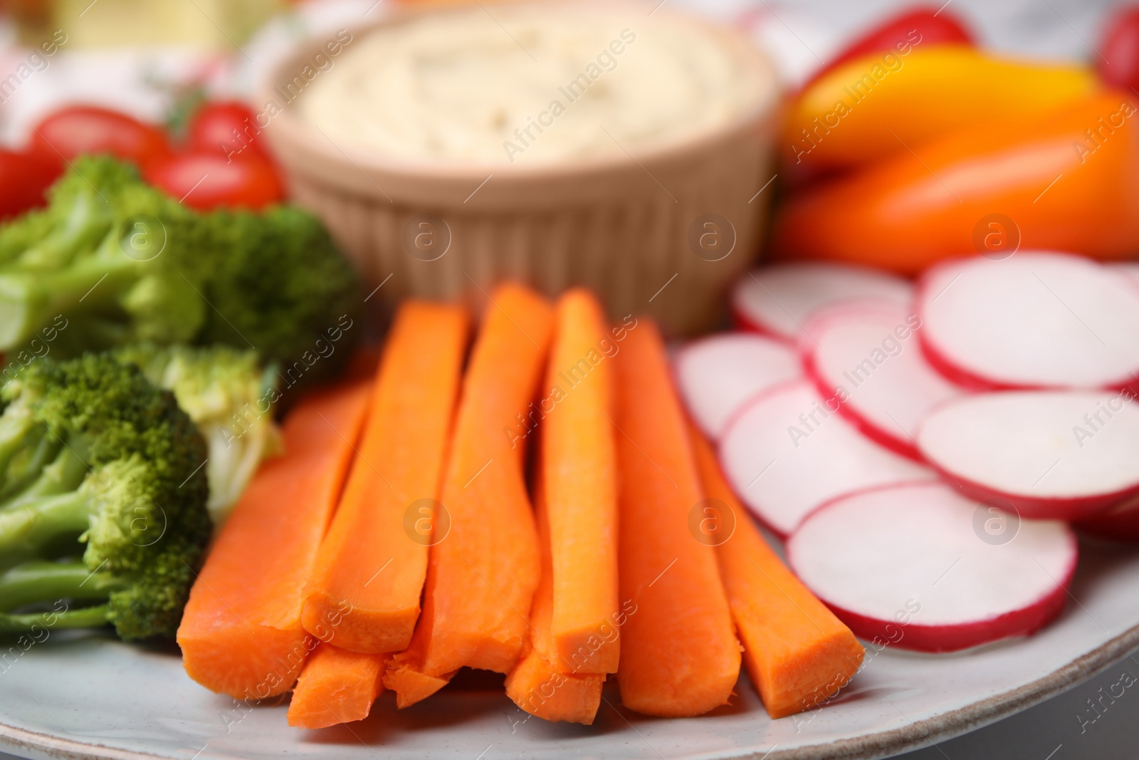 Photo of Plate with delicious hummus and fresh vegetables, closeup
