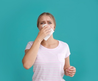 Photo of Young woman suffering from allergy on turquoise background