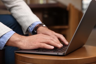 Photo of Man using modern laptop at table in cafe, closeup