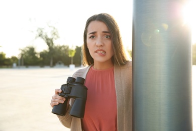 Photo of Jealous woman with binoculars spying on ex boyfriend outdoors