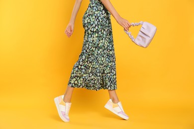 Photo of Woman with stylish bag on yellow background, closeup