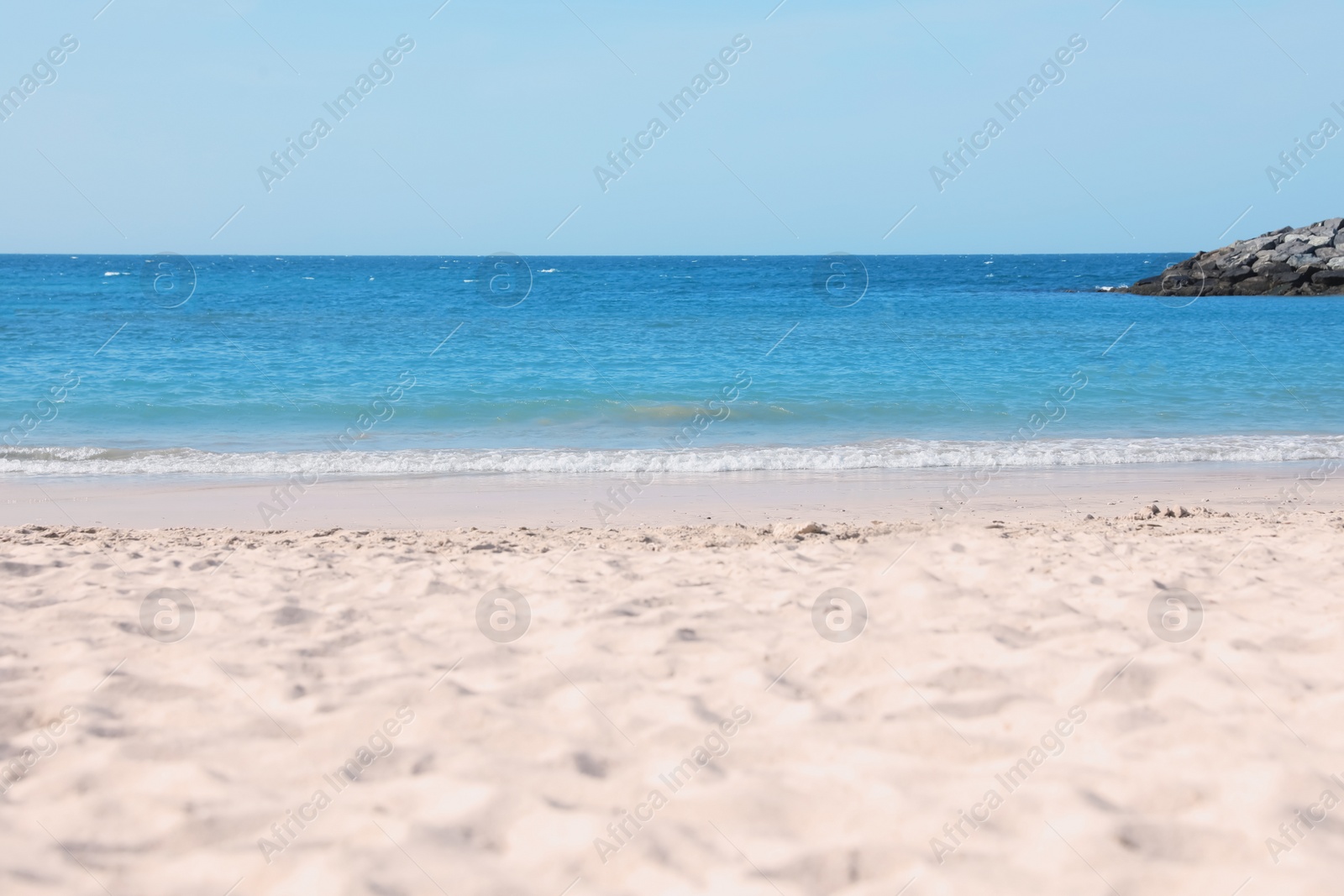 Photo of Picturesque view of beautiful beach with stone breakwater on sunny day