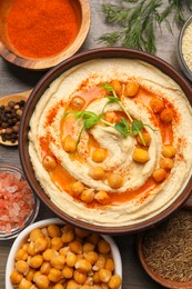 Photo of Delicious hummus with chickpeas and different ingredients on wooden table, flat lay