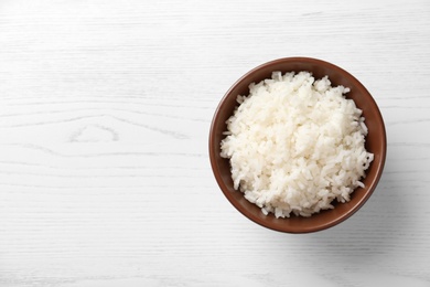 Photo of Bowl of boiled rice on wooden background, top view with space for text