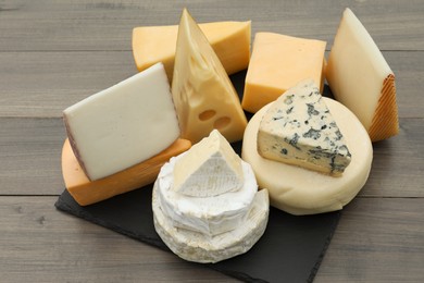 Different types of delicious cheeses on wooden table