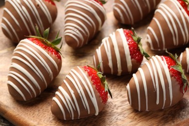 Photo of Delicious chocolate covered strawberries on wooden board, closeup