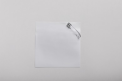 Photo of Paper note attached with safety pin on white background, top view